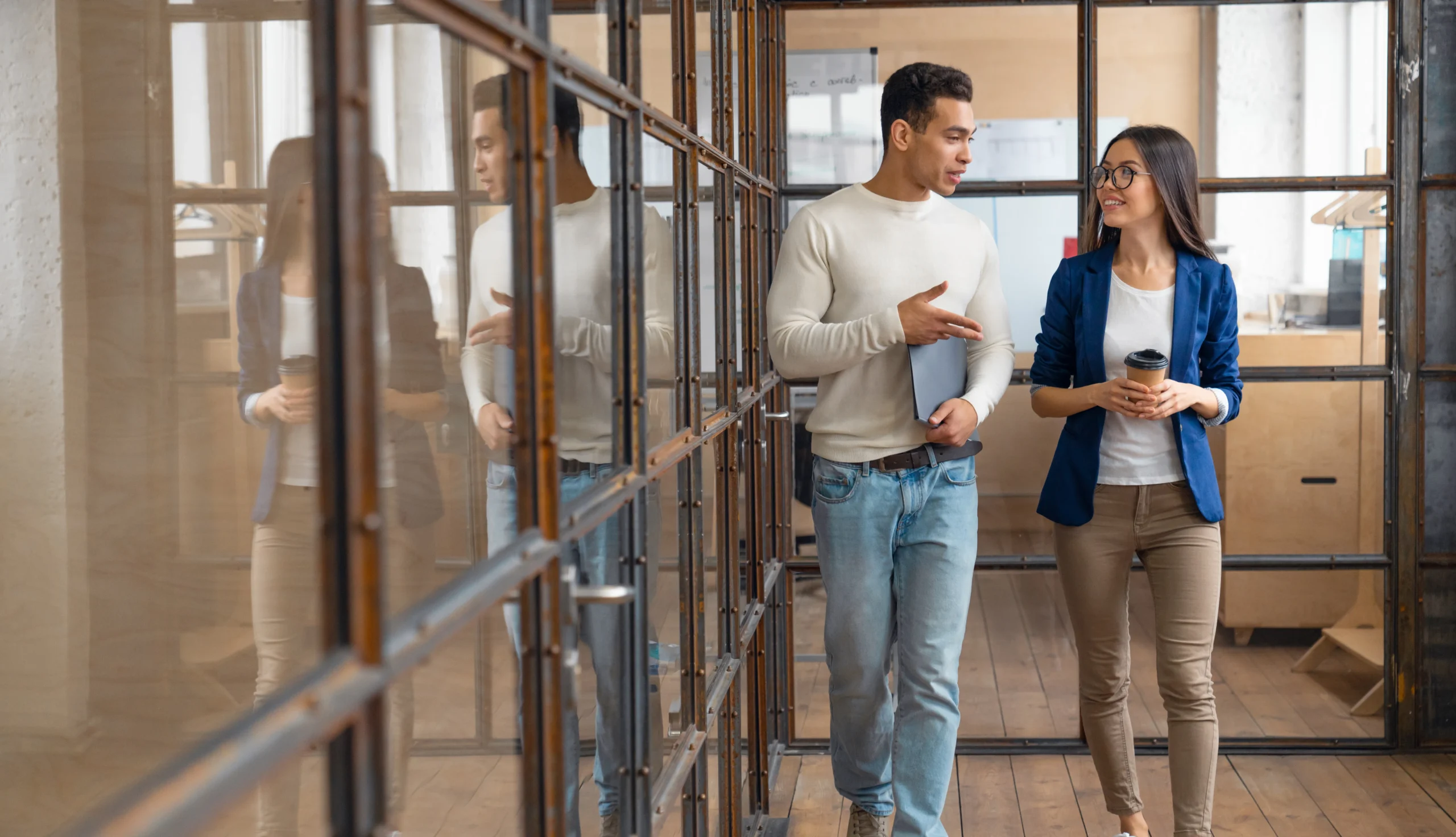 Der Blick in die Zukunft // A man and woman walking and discussing a project in an office building