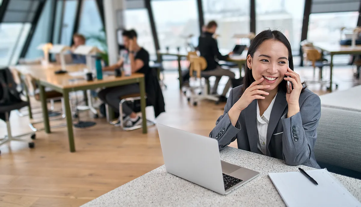 Wie Low-Code und KI die Modernisierung von IT-Systemen neu definieren // Young Asian business woman talking on mobile phone in big modern office
